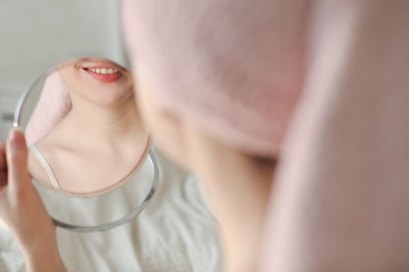a woman or girl looks at her teeth in the mirror